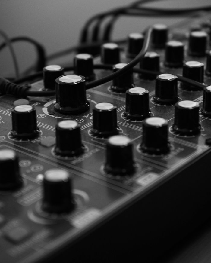 embark Grayscale close-up image of knobs on an audio mixer panel in a sound studio.
