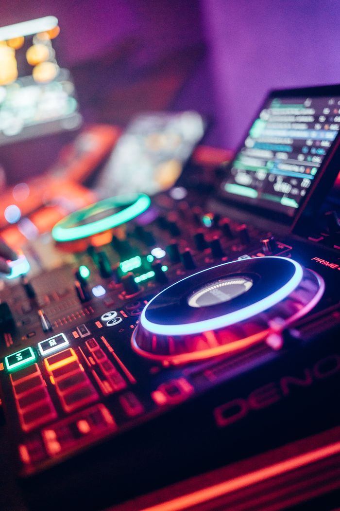 Colorful DJ equipment illuminated with neon lights in a lively nightclub setting.