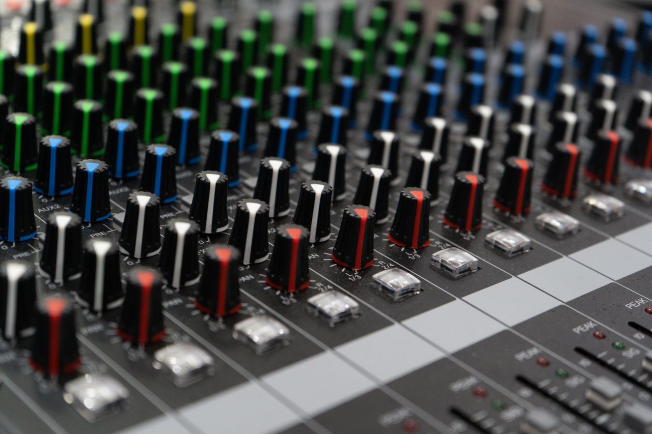 Detailed view of colorful dials on an audio mixing console, showcasing sound control technology.